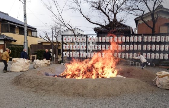 神戸宗社の中で4人の男性が木を投げて燃やしている